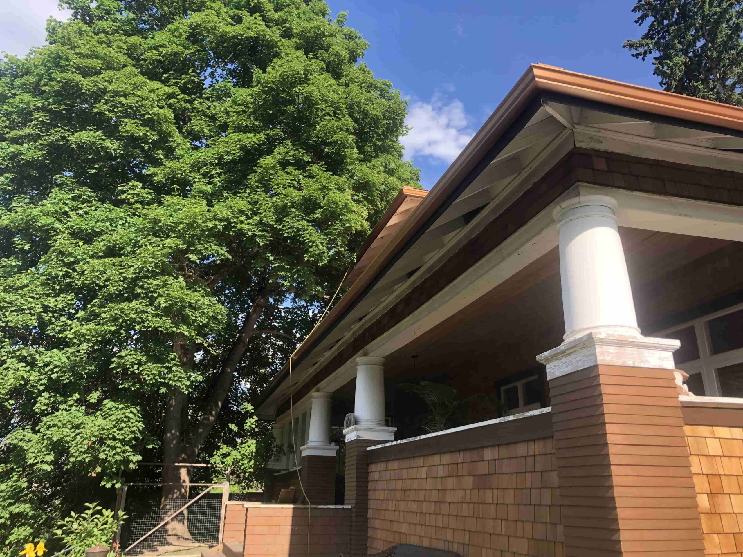New aluminum gutter system being installed on a residential roof during spring.